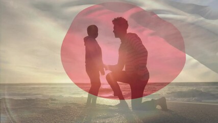 On beach, silhouetted couple with Japanese flag overlay, watching sunset animation - Powered by Adobe