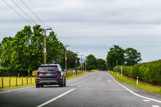 A black Hyundai SUV drives along a quiet rural road in the North Island of New Zealand