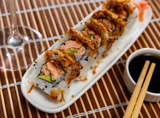 Rolls with salmon fish avocado and fried onions with bowl of soy sauce