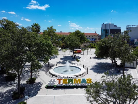 Vibrant capture of the heart of Termas de Rio Hondo, showing its iconic sign, the elegant casino, the luxury hotel, and the bustling main square.