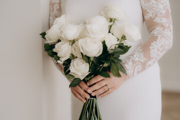 Beautiful bride holds white bouquet. bouquet from white rosses in woman's hands.