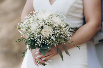 bouquet from white rosses in woman's hands. Beautiful bride holds white bouquet.