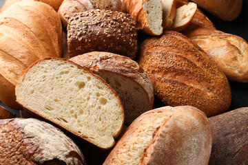 Whole and cut loafs of bread on table, closeup