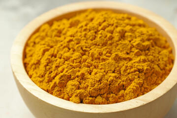 Turmeric powder in bowl on light table, closeup