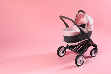 Stylish doll stroller on pink background, space for text. Kid's toy