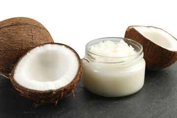 Organic coconut cooking oil in glass jar and fresh fruits on black table against white background
