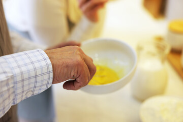 Senior man whisking eggs in kitchen, closeup
