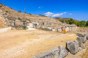 A rocky hillside with a stone wall and a few buildings. Ruins of the ancient city of Philippi, Greece