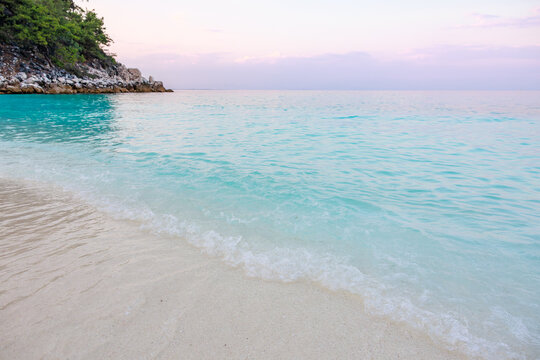A beautiful beach with a blue ocean and a white cliff