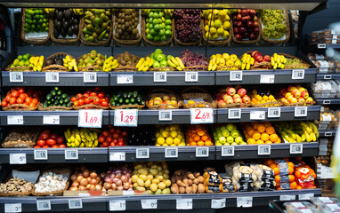 Large assortment of fresh colorful fruits and vegetables on shelves in supermarket.