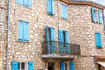 A medieval stone building with French Blue colored shutters on windows and balconies in the hill town of Gourdon, Alpes-Maritimes, France.