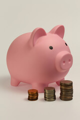 Close up of pink piggy bank with stack of coins.