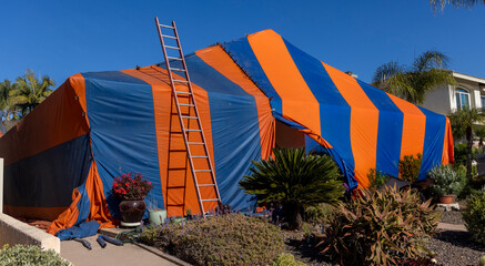 Far shot of a house with a fumigation tent in orange and blue stripes © F Armstrong Photo