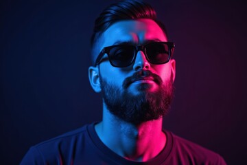 Obraz premium Stylish bearded man wearing sunglasses in moody neon lighting with blue and pink tones, modern fashion portrait with futuristic cyberpunk aesthetic and confident attitude