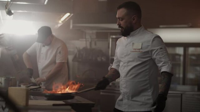 Man chef cooking dish with flames in restaurant kitchen