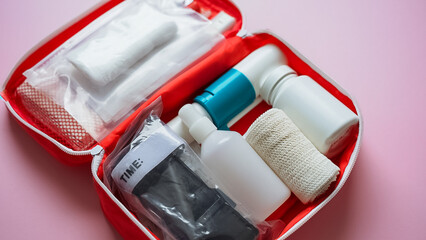A bright red first aid kit that is filled to the brim with various bottles and an assortment of...
