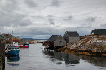 Quaint lobster fishing village of Peggy's Cove, near Halifax, Nova Scotia, Canada. Rocky seaside shores with fishing boats and lobster traps during a cloudy autumn day.