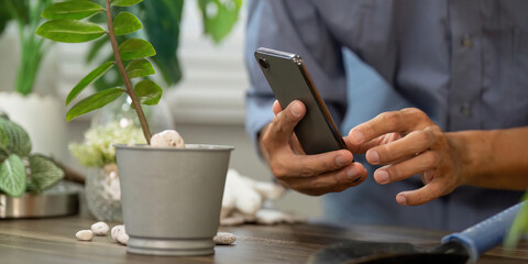 Gardening and Digital Care. A gardener using a smartphone to research plant care practices.