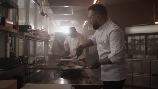 Professional man chef cooking dish in kitchen with colleagues