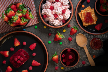 desserts, sweets, jelly, and strawberry jam on a black ceramic table decorated with strawberries