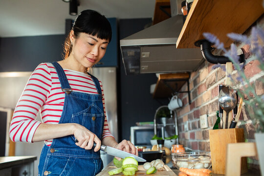Close up of woman cutting vegetables in modern kitchen - Powered by Adobe