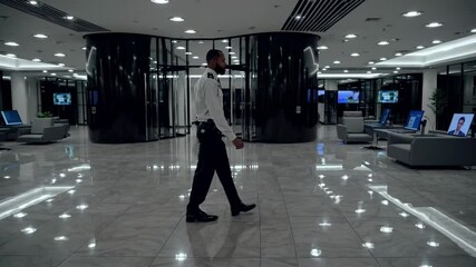 Wide-angle shot of a modern lobby with a security guard walking, emphasizing sleek design and surveillance, reminiscent of a corporate video.