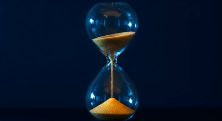 Hourglass With Amber Sand Flowing On Dark Background