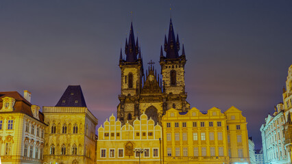 Fototapeta premium Prague, Czech Republic, at night features the iconic Prague Astronomical Clock tower, brightly lit and dominating the Old Town Square, with a deep blue sky providing a dramatic backdrop.