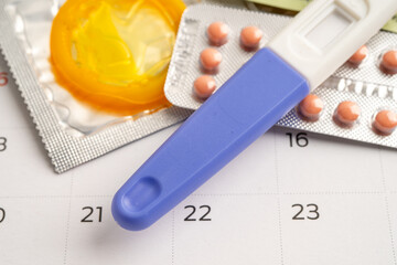 Pregnancy test and birth control pills on calendar, contraception health and medicine.