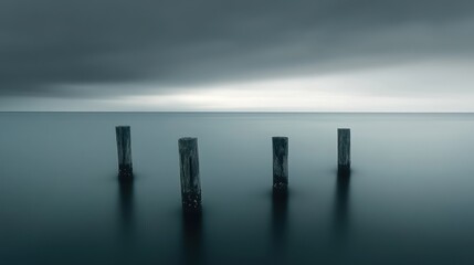 Serene ocean, four weathered pilings, calm water, moody sky, tranquil landscape