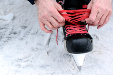 Man ties his shoelaces on hockey skates on an ice skating rink. Hockey equipment.
