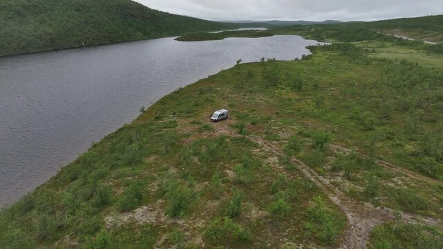 Aerial view of a van in the vast green landscape of Masi, Norway, near calm waters