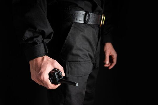 police officer's hand holding a radio station on his belt, close-up. Details about the weapons and special equipment of a police officer or security guard