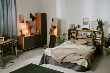 Sunlight gently illuminating a cozy bedroom featuring a neatly made bed, wooden furniture, and...