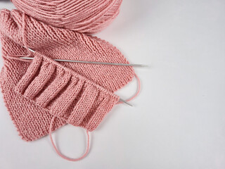 Pink knitting in progress. knitting needles and neat loops creating a textured pattern. a ball of soft wool yarn creating a cozy atmosphere. themes of handicrafts, creativity, knitting and hobbies.