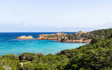Scenic view of Cala Andreani on Caprera Island, Italy. The turquoise Mediterranean sea and lush juniper bushes along the coast. The emerald waters and rocky formations. Stunning natural landscape.