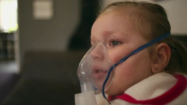 Asthmatic young girl receives nebulized ventolin by face mask, medical