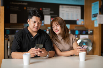 Fototapeta premium young couple using phone in laundry shop