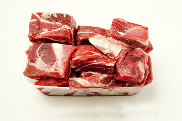 Fresh raw beef meat in a plastic container, isolated on a light background. Ideal for cooking, meal preparation, Eid celebrations, and traditional recipes.