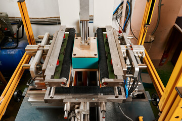 Innovative semi-automatic machine expertly wrapping rectangular boxes in a bustling packaging facility