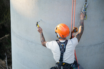 Rope access technician working at height, performing maintenance on concrete structure