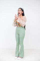 Surprised young Asian woman in floral corset and green pants with open mouth and animated hand gesture in profile