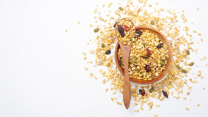 Top view of granola with oats, nuts, and dried fruits on wooden plate and spoon isolated on white...