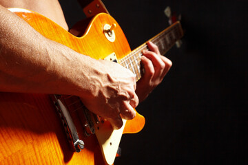 Posing hands of rock guitarist playing the guitar on dark stage.