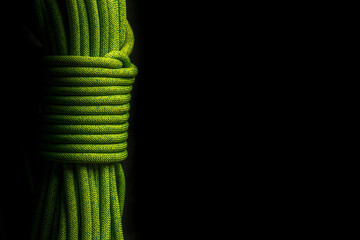 Green climbing rope on black background
