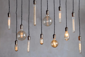 Vintage edison bulbs hanging against gray background illuminating with warm light
