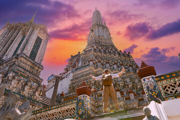 Majestic wat arun with man and backpack tourist at sunset in Bangkok, iconic temple architecture...
