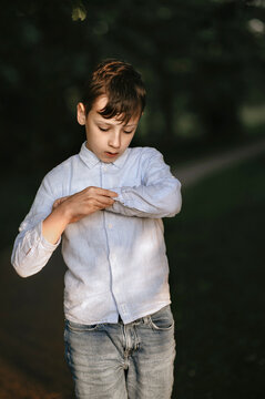 Boy fastens button on cuff.