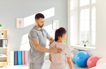 Doctor osteopath examining patient in rehabilitation clinic. Young male physiotherapist doing...