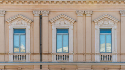 Obraz premium old yellow facade of house with three brown vintage wooden windows in retro italian european style